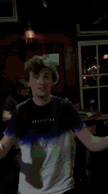 a man wearing a hollister shirt is dancing in a dark room .