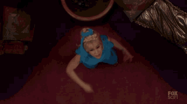 a woman in a blue dress is crawling on the floor in a room .