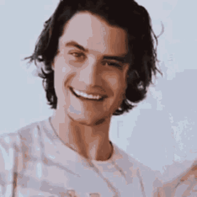 a young man with long hair is smiling at the camera .