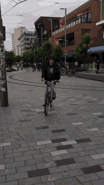 a man is riding a bike down a street with a building in the background that says ' a ' on it