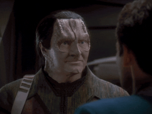 a man with a mask on his face says thank you to another man