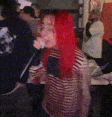 a woman with red hair is singing into a microphone in a crowd .
