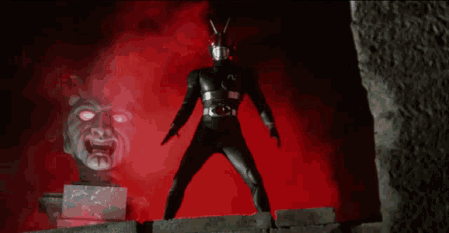 a man in a black superhero costume is standing in front of a red background