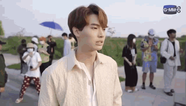 a young man is standing on a sidewalk in front of a group of people .