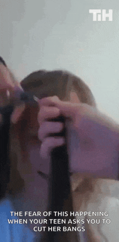 a person is cutting a woman 's hair with a pair of scissors
