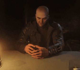 a bald man in a leather jacket sits at a table