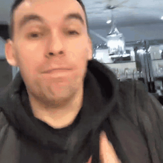 a man wearing a black jacket and a black shirt is making a funny face