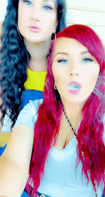 a woman with red hair is smoking a cigarette next to another woman with blue eyes
