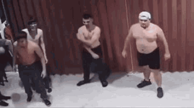 a group of men without shirts are dancing on a stage .