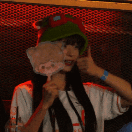 a woman wearing a green hat and a white shirt is holding a cartoon character on a stick ..