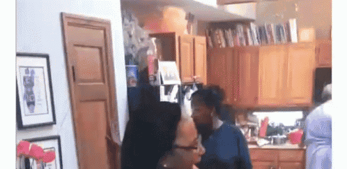 a couple of women are standing in a kitchen talking .