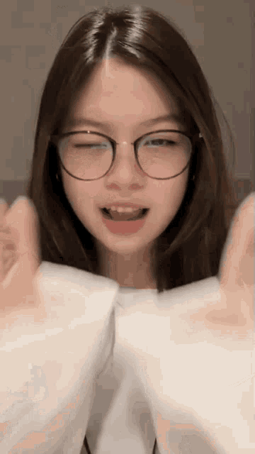 a young girl wearing glasses and a white shirt is making a funny face