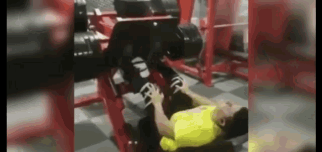 a man in a yellow shirt is laying on the floor in a gym .