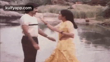 a man and woman are dancing in the water .
