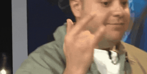 a man in a green jacket is making a funny face with his finger