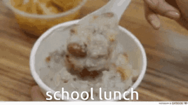 a person is holding a bowl of school lunch with a spoon in it