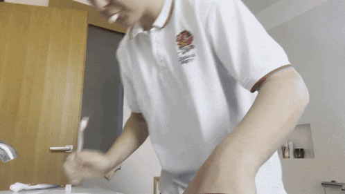 a man brushing his teeth in a white shirt with the word england on it