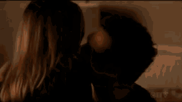 a man and a woman are kissing in a dark room on a bed .