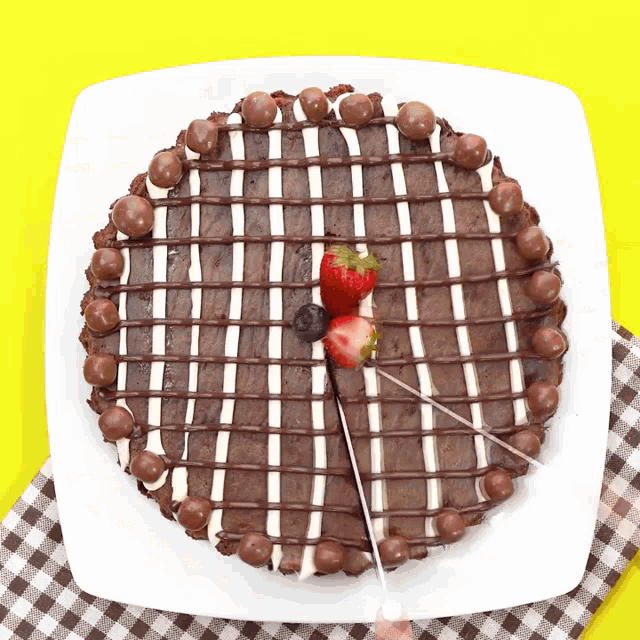 a chocolate cake with strawberries and blueberries on a white plate