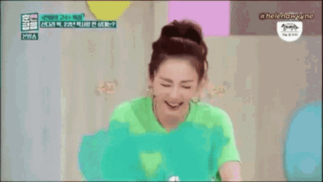 a woman in a green shirt is laughing with letters around her