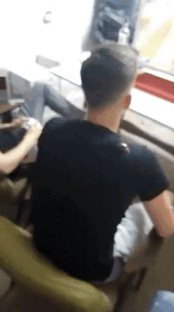 a man in a black shirt is sitting on a chair