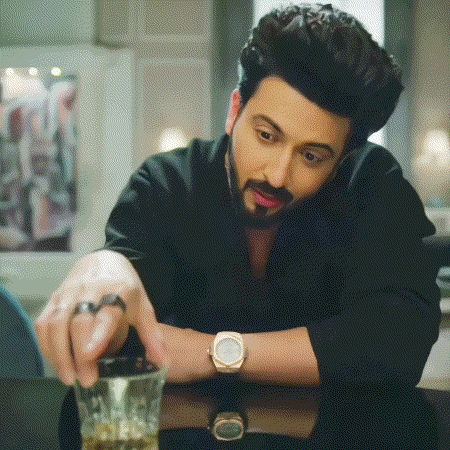a man wearing a watch is sitting at a table with a glass of whiskey