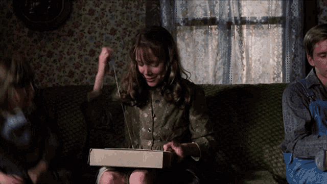 a woman sitting on a couch holding a box