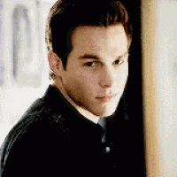 a young man in a black shirt is leaning against a wall .