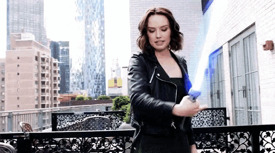 a woman in a leather jacket is holding a light saber .