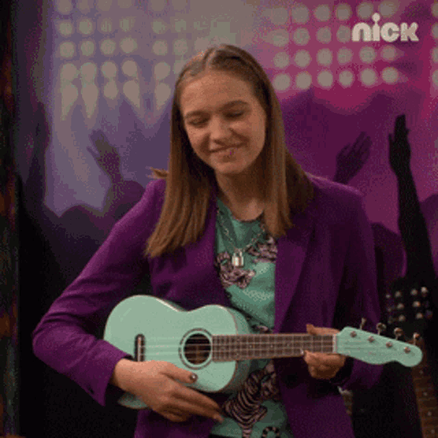 a girl in a purple jacket is holding a guitar in front of a nick poster