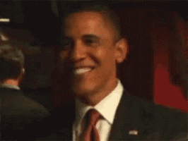 a man in a suit and tie is smiling while standing in front of a red curtain .