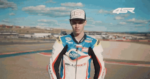 a man wearing a jacket that says acer stands on a race track