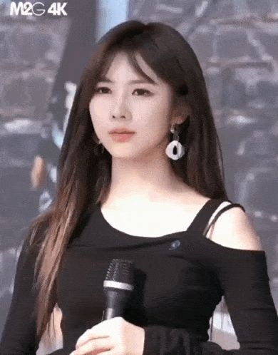 a woman in a black shirt is holding a microphone in her hand