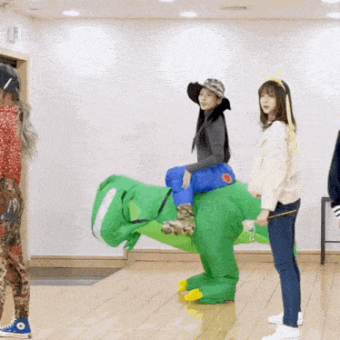 a woman riding on the back of a green dinosaur