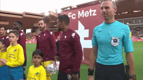 a group of soccer players are standing in front of a banner that says fc metz