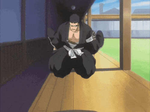 a man in a black kimono is kneeling down on a wooden floor