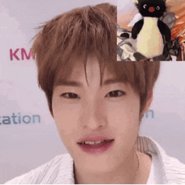 a close up of a person 's face with a stuffed penguin in the background .
