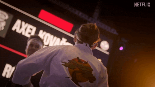 a man in a karate uniform stands in front of a netflix sign