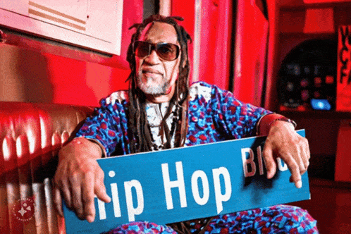 a man sitting on a couch holding a sign that says hip hop blvd.