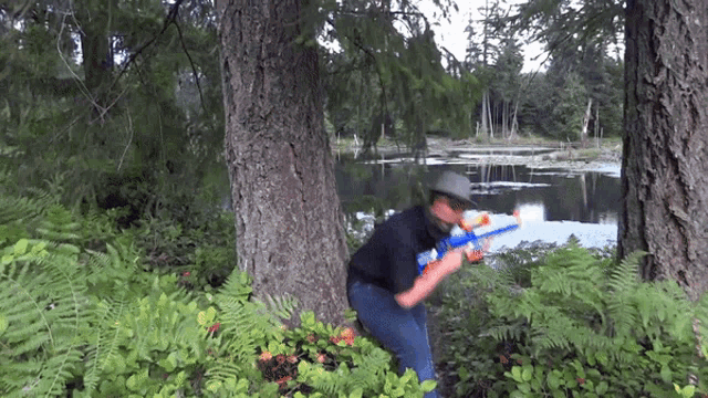 a man in a cowboy hat is holding a nerf gun