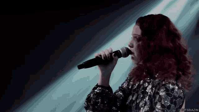 a woman with red hair is singing into a microphone on a stage .