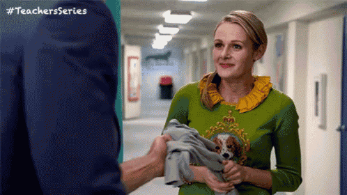 a woman in a green sweater is holding a dog and a towel .