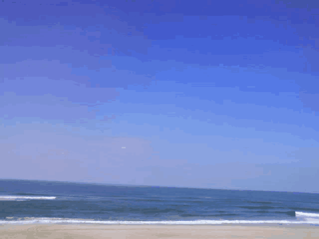a beach with a clear blue sky and waves crashing on the sand