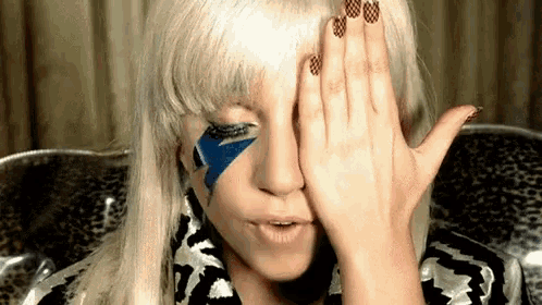 a woman covering her face with her hand while wearing a leopard print shirt
