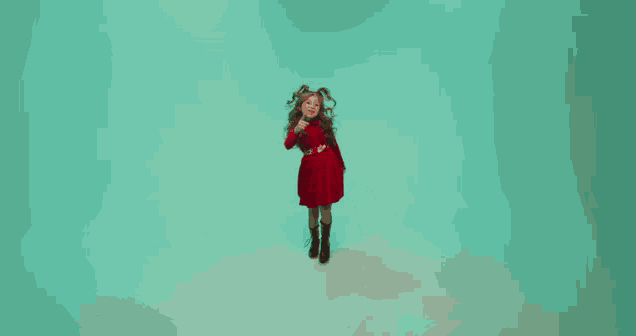 a little girl in a red dress is jumping in the air on a blue background
