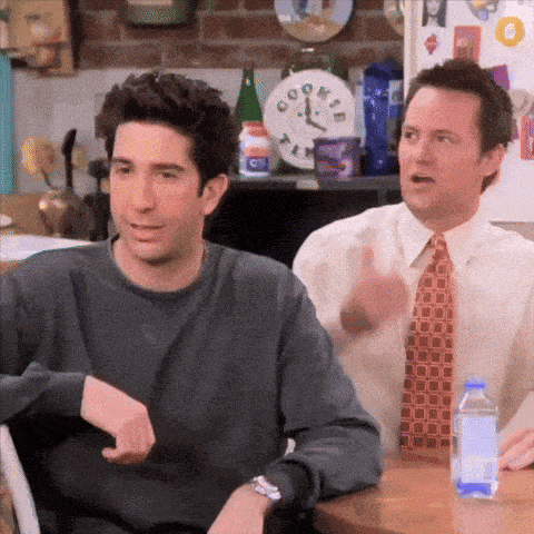 two men are sitting at a table in front of a clock that says cook 's on it