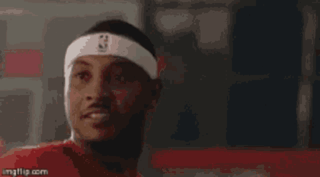 a man wearing a headband with a nba logo on it is looking at the camera .