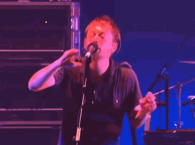 a man is singing into a microphone on a stage in front of a keyboard .