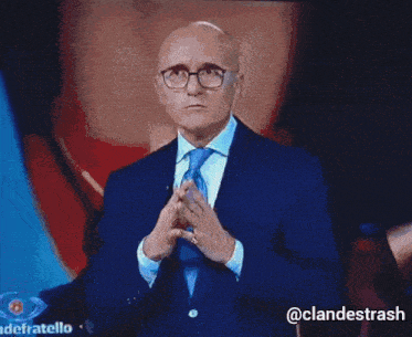 a man in a suit and tie is standing in front of a screen that says @clandetsrash