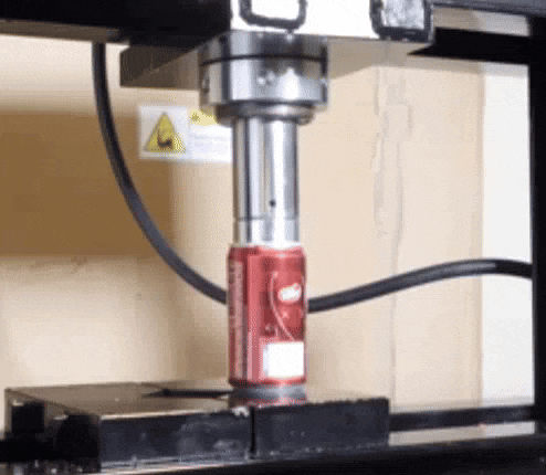 a can of soda is being pressed into a machine .